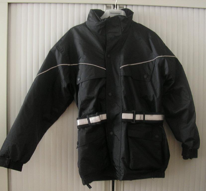 PARKA POUR HOMMES, EN TISSU DE FIBRES SYNTHÉTIQUES (POLYAMIDE) ENDUIT SUR LA FACE INTERNE DE MATIÈRE PLASTIQUE NON ALVÉOLAIRE DE FAÇON PERCEPTIBLE À L'OEIL NU, TEINT UNIFORMÉMENT, DESCENDANT JUSQU'À MI-CUISSE. 

CETTE PARKA COMPORTE UN COL MONTANT DOUBLÉ DE VELOURS, UN CAPUCHON DISSIMULÉ DANS LE COL BORDÉ D'UN CORDON COULISSANT SUR TOUT SON POURTOUR, UNE OUVERTURE COMPLÈTE SUR LE DEVANT SE FERMANT GAUCHE SUR DROITE AU MOYEN D'UNE FERMETURE À GLISSIÈRE RECOUVERTE D'UNE PATTE BOUTONNÉE, UNE DOUBLURE COMPLÈTE MATELASSÉE AMOVIBLE ET DES MANCHES LONGUES RESSERRÉES À LEUR EXTRÉMITÉ PAR UN BORD ÉLASTIQUE AINSI QUE PAR UNE PATTE DE SERRAGE MUNIE DE VELCRO. 

EN OUTRE, CETTE PARKA PRÉSENTE DEUX POCHES POITRINE AVEC RABAT BOUTONNÉ, DEUX POCHES LATÉRALES À SOUFFLET AVEC RABAT SITUÉES SOUS LA TAILLE ET UNE POCHE INTÉRIEURE AVEC VELCRO DU CÔTÉ GAUCHE.

ENFIN CE VÊTEMENT EST RESSERRÉ À LA TAILLE PAR UN ÉLASTIQUE ET PAR UNE CEINTURE, POURVUE D'UNE BANDE AUTORÉFLÉCHISSANTE ET RÉGLABLE À DROITE ET À GAUCHE PAR UNE BOUCLE PLASTIQUE ET UNE BANDE VELCRO, QUI S'INSÈRE DANS DES PASSANTS PRÉVUS À CET USAGE.

LA BASE DU VÊTEMENT EST ÉLASTIQUÉE ET OURLÉE.