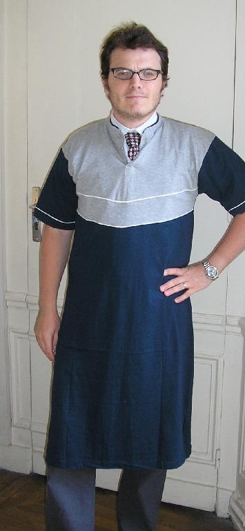 CHEMISE DE NUIT POUR HOMME, EN ETOFFE DE BONNETERIE DE COTON (100% COTON), DESTINEE A RECOUVRIR LE CORPS, DESCENDANT JUSQU’AUX MOLLET, AVEC UN PETIT COL MONTANT, GENRE COL MAO, AVEC UNE OUVERTURE PARTIELLE SUR LE DEVANT SE FERMANT GAUCHE SUR DROITE A L’AIDE DE BOUTONS, AVEC DES MANCHES COURTES POURVUES A LEURS EXTREMITES D’UN OURLET, AVEC UNE FENTE DE 15 CM ENVIRON DE CHAQUE COTE AU BAS DU VETEMENT, AVEC UN OURLET A LA BASE, AVEC UN LISERE FORMANT GARNITURE SUR LE DEVANT ET AU BAS DES MANCHES.