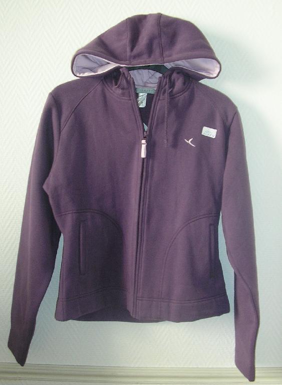 ENSEMBLE EN ETOFFE DE BONNETERIE GRATTEE DE COTON (56% COTON – 44% POLYESTER) COMPOSE:

- D'UN HAUT, GENRE GILET, DESTINE A RECOUVRIR LA PARTIE SUPERIEURE DU CORPS, DESCENDANT JUSQU’AUX HANCHES, AVEC UN CAPUCHON POURVU SUR SON POURTOUR D’UN CORDON COULISSANT RESSERRANT, AVEC DES MANCHES LONGUES MUNIES A LEURS EXTREMITES D’UN OURLET, AVEC UNE OUVERTURE COMPLETE SUR LE DEVANT SE FERMANT A L’AIDE D'UNE FERMETURE A GLISSIERE, AVEC DEUX POCHES LATERALES EXTERNES, AVEC UN OURLET A LA BASE. SEULE LA CAPUCHE COMPORTE UNE DOUBLURE.

- D'UN PANTALON DESCENDANT JUSQU'AUX CHEVILLES, SANS OUVERTURE, AVEC UN ELASTIQUE A LA TAILLE MUNIE D'UN CORDON COULISSANT RESSERRANT, AVEC DEUX POCHES EXTERNES GARNIES D’UN GALON DE COULEUR DIFFERENTE DE CELLE DU PANTALON (GARNITURE DE MINIME IMPORTANCE), AVEC UN OURLET A LA BASE.

LE HAUT ET LE PANTALON DONT DOTES D’UN LOGO PUBLICITAIRE IDENTIQUE.