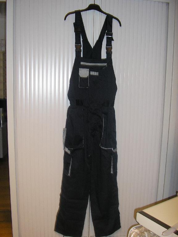 SALOPETTE A BRETELLES, EN TISSU 65% POLYESTER ET 35% COTON, POUR HOMME, COMPORTANT DES BRETELLES REGLABLES AVEC FERMETURE PAR BOUCLES EN MATIERE PLASTIQUE, SUR LE DEVANT UNE BAVETTE AVEC UNE GRANDE POCHE AVEC FERMETURE A GLISSIERE ET DES PETITES POCHES DONT UNE A SOUFFLET AVEC RABAT ET FERMETURE PAR BANDE VELCRO, AU DOS UNE BANDE DE TISSU RELIE LES BRETELLES A LA TAILLE DU VETEMENT, LA TAILLE EST ELASTIQUEE SUR LES COTES, OUVERTURE PARTIELLE DE CHAQUE COTE DE LA TAILLE AVEC BOUTONS, UNE GRANDE POCHE A SOUFFLET DE CHAQUE COTE DU VETEMENT AU NIVEAU DES HANCHES, UNE BRAGUETTE AVEC FERMETURE A GLISSIERE ET RABAT DE GAUCHE SUR DROITE, UNE PETITE POCHE A SOUFFLET AVEC RABAT ET BANDE VELCRO DE CHAQUE COTE DU VETEMENT AU NIVEAU DES CUISSES, UNE POCHE DE CHAQUE COTE DU VETEMENT AU NIVEAU DES FESSES, L'UNE AVEC FEMETURE A GLISSIERE ET L'AUTRE AVEC RABAT ET BANDE VELCRO, LA BASE DES JAMBES EST OURLEE AVEC UN CORDON RESSERANT A NOUER.