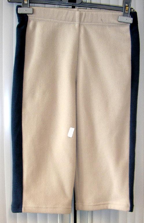 SURVÊTEMENT DE SPORT POUR ENFANTS EN ÉTOFFE DE BONNETERIE DE FIBRES SYNTHÉTIQUES (100% POLYESTER) GRATTÉE DE TYPE POLAIRE, NON DOUBLÉ, COMPOSÉ DE DEUX PIÈCES : 

- UN PULL-OVER, DESCENDANT JUSQU'AU-DESSOUS DE LA TAILLE, AVEC UN COL MONTANT, AVEC DEUX OUVERTURES PARTIELLES À L'ENCOLURE SE FERMANT CHACUNE PAR UNE FERMETURE À GLISSIÈRE, AVEC DES MANCHES LONGUES MUNIES D'UN BORD ÉLASTIQUE DE COULEUR CONTRASTÉE À LEUR EXTRÉMITÉ ET COMPORTANT LE MÊME BORD ÉLASTIQUE À LA BASE.
EN OUTRE, CE PULL PRÉSENTE DES EMPIÈCEMENTS DE BONNETERIE POLAIRE DE COULEUR CONTRASTÉE SUR LE DEVANT, LE DESSUS DES MANCHES AINSI QUE SUR LES CÔTÉS, UNE POCHE AVEC FERMETURE À GLISSIÈRE SUR LA MANCHE GAUCHE ET UNE INSCRIPTION BRODÉE FIGURANT UN LOGO PUBLICITAIRE SUR LA POITRINE CÔTÉ GAUCHE.

- UN PANTALON, TEINT UNIFORMÉMENT, DESCENDANT JUSQU'AUX CHEVILLES, DE COUPE SIMPLE, TENU À LA TAILLE PAR UNE BANDE ÉLASTIQUE, SANS OUVERTURE À LA TAILLE.
IL PRÉSENTE UNE BANDE DE BONNETERIE POLAIRE DE COULEUR CONTRASTÉE RAPPORTÉE SUR CHAQUE CÔTÉ ET UN OURLET À L'EXTRÉMITÉ DES JAMBES.