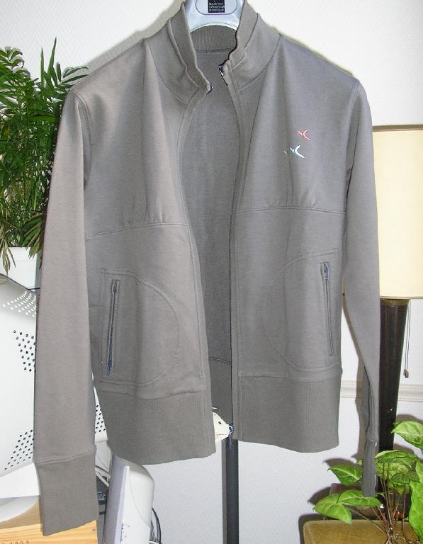 SURVÊTEMENT DE SPORT EN ÉTOFFE DE BONNETERIE MAJORITAIREMENT DE COTON (95% COTON - 5% ÉLASTHANNE), NON DOUBLÉ, COMPOSÉ DE DEUX PIÈCES :

- HAUT GENRE GILET, TEINT UNIFORMÉMENT, DESCENDANT JUSQU'AU-DESSOUS DE LA TAILLE, AVEC UN COL RAPPORTÉ EN BORD-CÔTES, AVEC UNE OUVERTURE COMPLÈTE SUR LE DEVANT SE FERMANT À L'AIDE D'UNE FERMETURE À GLISSIÈRE, AVEC DES MANCHES LONGUES MUNIES D'UN BORD-COTES À LEURS EXTRÉMITÉS, AVEC DEUX POCHES LATÉRALES SITUÉES AU-NIVEAU DE LA TAILLE SE FERMANT A L’AIDE D’UNE FERMETURE A GLISSIERE DOTEES D’UN PETIT BORD-CÔTES DE PART ET D’AUTRE DE LA FERMETURE A GLISSIERE, AVEC UN BORD-CÔTES RAPPORTÉ À LA BASE. 

- UN PANTALON, TEINT UNIFORMÉMENT, DESCENDANT JUSQU'AUX CHEVILLES, DE COUPE DROITE, AVEC UNE BANDE EN BORD-COTES ET UN CORDON COULISSANT RESSERRANT A LA TAILLE, SANS OUVERTURE, AVEC UNE POCHE LATERALE DE CHAQUE COTE AU NIVEAU DES HANCHES, AVEC UN OURLET A LA BASE

LE GILET ET LE PANTALON SONT DOTES D’UN LOGO PUBLICITAIRE BRODE.