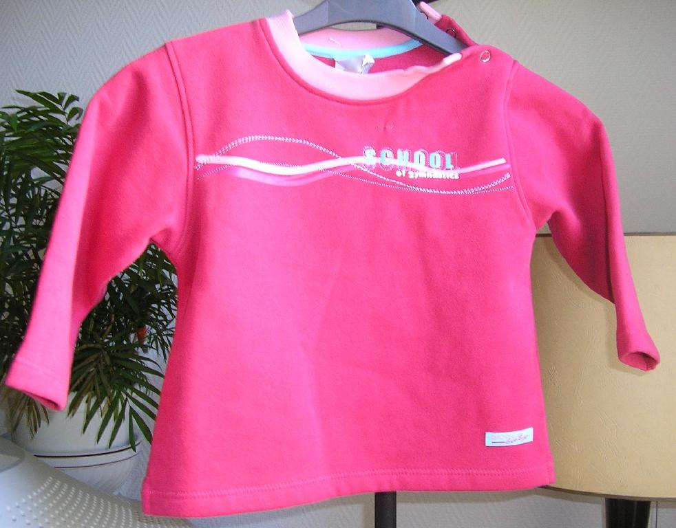 ENSEMBLE EN ETOFFE DE BONNETERIE GRATTEE DE COTON 100% COTON COMPOSE:

- D'UN HAUT, GENRE PULL-OVER, DESTINE A COUVRIR LA PARTIE SUPERIEURE DU CORPS, DESCENDANT JUSQU’AUX HANCHES, AVEC UNE ENCOLURE ARRONDIE, AVEC UNE OUVERTURE PARTIELLE SUR L’EPAULE GAUCHE SE FERMANT A L’AIDE DE BOUTONS-PRESSION, AVEC DES MANCHES LONGUES MUNIES A LEURS EXTREMITES D’UN OURLET, AVEC UNE FENTE DE 3 CM ENVIRON A LA BASE SUR CHAQUE COTE, AVEC UN OURLET A LA BASE, AVEC UN MOTIF DECORATIF SUR LA POITRINE ET UN LOGO PUBLICITAIRE AU BAS A GAUCHE DU VETEMENT.

- D'UN PANTALON DESCENDANT JUSQU'AUX CHEVILLES, SANS OUVERTURE, AVEC UN ELASTIQUE A LA TAILLE, AVEC UNE PETITE FENTE DE 3 CM ENVIRON DE CHAQUE COTE A LA BASE, AVEC UN OURLET A LA BASE, AVEC UN MOTIF DECORATIF IDENTIQUE AU NIVEAU DE LA HANCHE A DROITE ET UN LOGO PUBLICITAIRE AU BAS DU PANTALON.

L’ENCOLURE DU HAUT ET LA TAILLE DU PANTALON SONT DE COULEUR DIFFERENTE DE CELLE DE L’ENSEMBLE.