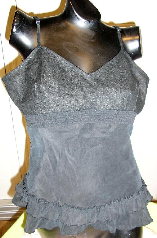 VÊTEMENT LÉGER POUR FEMMES DESTINÉ À RECOUVRIR LA PARTIE SUPÉRIEURE DU CORPS, DE TYPE BLOUSE, DESCENDANT JUSQU'AU-DESSOUS DE LA TAILLE ET CONFECTIONNÉE MAJORITAIREMENT EN TISSU DE SOIE. 
CETTE BLOUSE EST RÉALISÉE À PARTIR DE DEUX MATIÈRES : LA PARTIE SUPÉRIEURE JUSQU'AU-DESSOUS DE LA POITRINE EST EN TISSU DE LIN ET LA PARTIE INFÉRIEURE PARTANT SOUS LA POITRINE ET DESCENDANT JUSQU'À LA BASE EST EN SOIE.

CE VÊTEMENT COMPORTE UNE ENCOLURE DÉCOLLETÉE EN V, DE FINES BRETELLES AJUSTABLES, DES PINCES POITRINE, UNE PARTIE SMOCKÉE SOUS LA POITRINE ET UNE BASE VOLANTÉE.