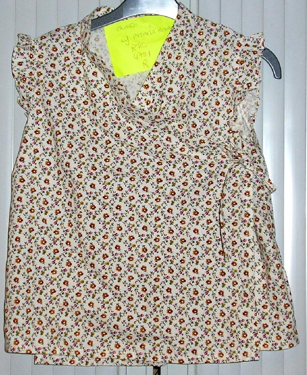 ENSEMBLE POUR FILLETTES COMPOSÉ D'UN PANTACOURT ET D'UN VÊTEMENT DESTINÉ À RECOUVRIR LA PARTIE SUPÉRIEURE DU CORPS GENRE BLOUSE-CHEMISIER RÉALISÉS DANS LE MÊME TISSU DE COTON, IMPRIMÉ DE MOTIFS FLEURIS ET CONDITIONNÉS ENSEMBLE POUR LA VENTE AU DÉTAIL : 

- LE PANTALON EST DE COUPE DROITE, DESCEND JUSQU'AU-DESSOUS DES GENOUX ET COMPORTE UNE TAILLE ÉLASTIQUÉE. L'EXTRÉMITÉ DES JAMBES PRÉSENTE UN PETIT GALON FRONCÉ DU MÊME TISSU.

- LA BLOUSE DESCEND JUSQU'AUX HANCHES ET PRÉSENTE UN REVERS SUR LE POURTOUR DE L'ENCOLURE, UNE OUVERTURE COMPLÈTE SUR LE DEVANT SE FERMANT DROITE SUR GAUCHE, COMME UN CACHE-CŒUR, PAR DEUX BOUTONS-PRESSION SITUÉS SUR LE CÔTÉ GAUCHE ET UN PETIT BOUTON INTERNE SITUÉ DU CÔTÉ DROIT.
EN OUTRE, ELLE COMPORTE DEUX PETITS MANCHERONS RÉALISÉS À PARTIR D'UN GALON FRONCÉ DU MÊME TISSU, UN PETIT RUBAN À NOUER DÉCORATIF SITUÉ AU NIVEAU DE LA FERMETURE CÔTÉ GAUCHE ET UN OURLET À LA BASE.

LES COMPOSANTS DE L'ENSEMBLE SONT DE MÊME STRUCTURE, STYLE, COULEUR ET COMPOSITION.