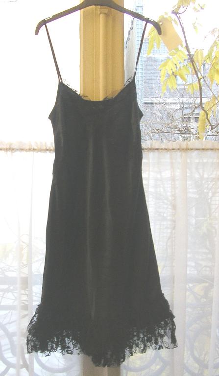 VETEMENT POUR FEMME, GENRE ROBE, EN TISSU SATINE DE SOIE (100% SOIE) DE FORME CINTREE A LA TAILLE PUIS EVASEE VERS LE BAS, DESTINE A COUVRIR LA PARTIE SUPERIEURE DU CORPS, DESCENDANT JUSQU’AUX GENOUX, AVEC DEUX FINES BRETELLES, AVEC UNE ENCOLURE EN « V » DOTEE D’UN GALON EN DENTELLE, AVEC DEUX LARGES VOLANTS EN DENTELLE FRONCES ET SUPERPOSES A LA BASE DU VETEMENT, AVEC UN BORD ROULOTTE A LA BASE.

LES BORDURES DES VOLANTS EN DENTELLE NE SONT PAS CONFECTIONNEES.

LONGUEUR ENVIRON 85 CM