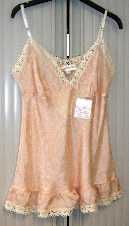 PYJAMA POUR FEMMES CONFECTIONNÉ EN TISSU LÉGER DE SOIE, IMPRIMÉ, COMPOSÉ DE DEUX VÊTEMENTS ASSORTIS, DE COUPE AMPLE ET SANS ÉLÉMENTS D'INCONFORT : 

- UN VÊTEMENT DESTINÉ À RECOUVRIR LA PARTIE SUPÉRIEURE DU CORPS, DE TYPE CARACO, DESCENDANT SOUS LA TAILLE, AVEC DE FINES BRETELLES RÉGLABLES, UN PROFOND DÉCOLLETÉ EN V, DES DÉCOUPES POITRINE FRONCÉES À LA BASE ET UN PETIT NŒUD DÉCORATIF AU MILIEU DU DÉCOLLETÉ.
LE POURTOUR DU DÉCOLLETÉ, DES EMMANCHURES ET DU DOS EST BORDÉ D'UN GALON UNICOLORE CONFECTIONNÉ EN CROCHET.

LA BASE DE CE VÊTEMENT PRÉSENTE UNE BANDE DE TISSU RAPPORTÉE VOLANTÉE SE FINISSANT PAR LE MÊME GALON EN CROCHET QUE LE DÉCOLLETÉ.

- UN SHORT, SANS OUVERTURE, AVEC UN BORD ÉLASTIQUE À LA TAILLE AINSI QU'UN PETIT NŒUD DÉCORATIF SUR LE DEVANT. 

LA BASE DU SHORT EST BORDÉE D'UN GALON UNICOLORE CONFECTIONNÉ EN CROCHET ET COMPORTE UN PETIT NŒUD DÉCORATIF DE CHAQUE CÔTÉ.