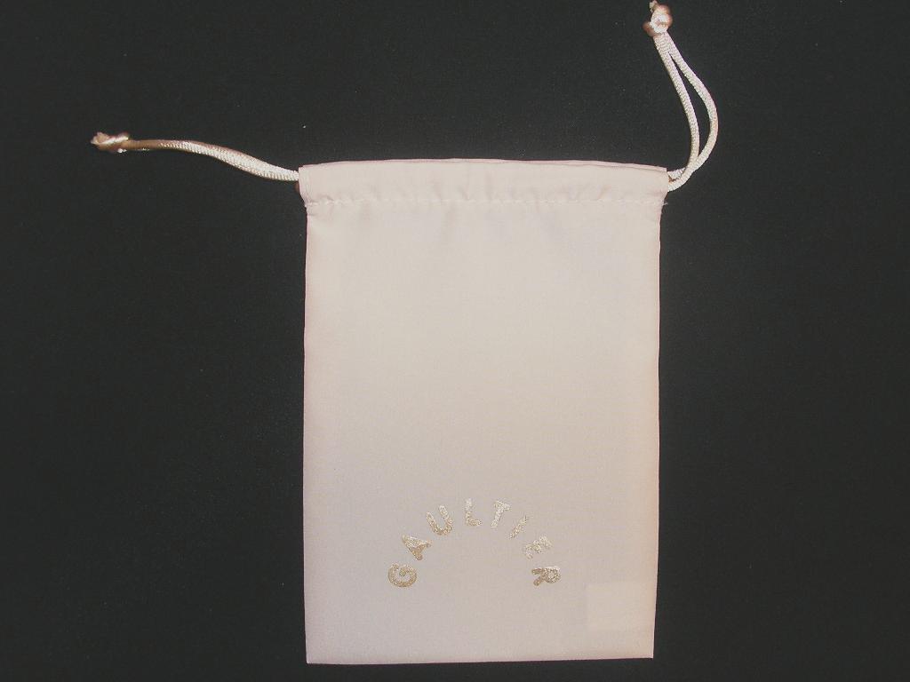 POCHETTE EN TISSU DE FIBRE SYNTHÉTIQUE (100% POLYESTER) DE FORME RECTANGULAIRE D'UNE LONGUEUR DE 14.5 CM ENVIRON ET D'UNE LARGEUR DE 10 CM ENVIRON, AVEC DEUX LIENS RESSERRANT AU SOMMET PERMETTANT LA FERMETURE DE L'ARTICLE ET AVEC LE LOGO DE LA MARQUE SUR UNE FACE.

CETTE POCHETTE EST DESTINÉE À CONTENIR UN LAIT PARFUMÉ POUR LE CORPS QUI SERA DISTRIBUÉ À TITRE GRATUIT EN TANT QU'ÉCHANTILLON.
ELLE EST PRÉSENTÉE DANS UN SACHET EN MATIÈRE PLASTIQUE.