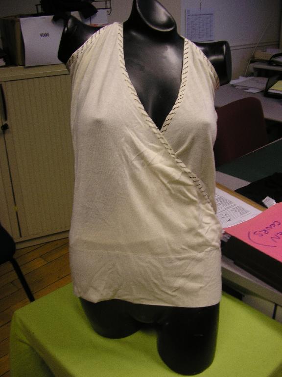 VETEMENT DESTINE A RECOUVRIR LA PARTIE SUPERIEURE DU CORPS, GENRE PULLOVER, POUR FEMME, EN BONNETERIE LEGERE 70% BAMBOU ET 30% VISCOSE, SANS MANCHES, COMPORTANT UNE ENCOLURE EN V, SE PROLONGEANT JUSQU'A LA TAILLE EN SE CROISANT AU NIVEAU DE LA POITRINE, DE LARGES EMMANCHURES AVEC BRETELLES, LA BASE DU VETEMENT EST EN BORD-COTES, BRODERIE BORDURE DE L'ENCOLURE JUQU'A LA TAILLE ET BRETELLES.