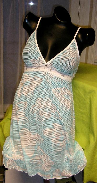 COMBINAISON POUR FEMMES EN BONNETERIE DE FIBRES SYNTHÉTIQUES (83% NYLON - 17% ÉLASTHANNE), IMPRIMÉE DE MOTIFS FLEURIS, LÉGÈREMENT TRANSLUCIDE, DESCENDANT JUSQU'À MI-CUISSE ET COMPORTANT UN PROFOND DÉCOLLETÉ EN V BORDÉ PAR UN GALON UNICOLORE QUI SE PROLONGE PAR DE FINES BRETELLES, UNE BANDE DE DENTELLE DE COULEUR CONTRASTÉE RAPPORTÉE SOUS LA POITRINE ET UNE BASE SURFILÉE LÉGÈREMENT VOLANTÉE.