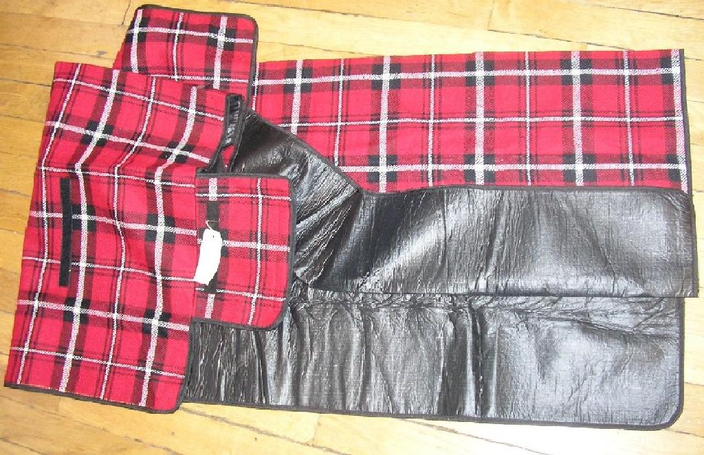 COUVERTURE EN FIBRES SYNTHÉTIQUES, GENRE PLAID DE PICNIC, DE FORME RECTANGULAIRE 175CM * 135 CM ENVIRON, AVEC DEUX FACES DE MATIÈRE DIFFÉRENTES:
  - FACE SUPÉRIEURE EN TISSU (100% ACRYLIQUE) 
  - FACE EN CONTACT AVEC LE SOL EN MATIÈRE PLASTIQUE (100% PVC).
CETTE COUVERTURE COMPORTE UN FIN REMBOURRAGE EN MOUSSE ENTRE SES DEUX FACES ET UN BIAIS SUR TOUT SON POURTOUR.
ELLE EST MUNIE DE BANDES VELCRO ET D'UNE POIGNÉE POUR FACILITER SON PLIAGE ET SON TRANSPORT.