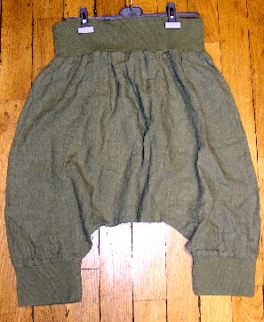 PANTALON, NON RECONNAISSABLE COMME ÉTANT POUR HOMMES OU POUR FEMMES, EN TISSU DE LIN, TEINT UNIFORMÉMENT, SANS OUVERTURE À LA TAILLE ET DESCENDANT JUSQU'AUX MOLLETS.

CE PANTALON PRÉSENTE UNE ENTREJAMBE TRÈS BASSE DONNANT UN ASPECT BOUFFANT, DE TYPE SAROUEL ET COMPORTE UN LARGE BORD-CÔTE RESSERRANT À LA TAILLE AINSI QU'À L'EXTRÉMITÉ DES JAMBES.