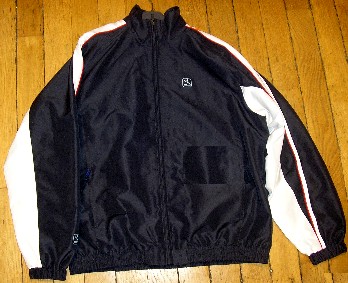 SURVÊTEMENT DE SPORT EN TISSU DE FIBRES SYNTHÉTIQUES (100% POLYESTER), NON RECONNAISSABLE COMME ÉTANT POUR HOMMES OU POUR FEMMES, COMPOSÉ D'UNE VESTE ET D'UN PANTALON :

- LA VESTE DESCEND JUSQU'AUX HANCHES ET COMPORTE UN COL MONTANT, UNE OUVERTURE COMPLÈTE SUR LE DEVANT SE FERMANT AU MOYEN D'UNE FERMETURE À GLISSIÈRE, UNE DOUBLURE COMPLÈTE EN MAILLES FILET, DES MANCHES LONGUES RESSERRÉES À LEUR EXTRÉMITÉ PAR UN BORD ÉLASTIQUE, DEUX POCHES LATÉRALES AVEC FERMETURE À GLISSIÈRE ET UN BORD ÉLASTIQUE À LA BASE. 

LA VESTE COMPORTE DES EMPIÈCEMENTS DE TISSU DE COULEUR CONTRASTÉE COUSUS HORIZONTALEMENT SUR LE DESSUS ET LE DESSOUS DES MANCHES.
EN OUTRE, LE DESSUS DES MANCHES PRÉSENTE DES GALONS DE COULEUR CONTRASTÉE COUSUS LONGITUDINALEMENT.

ENFIN, CETTE VESTE PRÉSENTE UN LOGO PUBLICITAIRE IMPRIMÉ À L'EXTRÉMITÉ DES MANCHES, SUR LA POITRINE CÔTÉ GAUCHE ET AU MILIEU DU HAUT DU DOS.

- LE PANTALON FAIT L'OBJET D'UN CLASSEMENT SÉPARÉ (CF RTC N°FR-E4-2006-000291-02).
