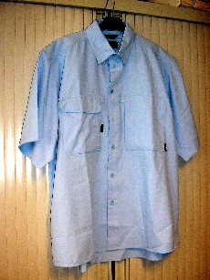 VETEMENT DESTINE A RECOUVRIR LA PARTIE SUPERIEURE DU CORPS, GENRE CHEMISETTE, POUR HOMME, EN TISSU 100% POLYESTER, COMPORTANT UN COL CHEMISIER AVEC BOUTON DISSIMULE ENTRE LES DEUX PARTIES DES POINTES, DES MANCHES COURTES AUX EXTREMITES OURLEES, UNE OUVERTURE COMPLETE SUR LE DEVANT AU MILIEU AVEC DES BOUTONS SE FERMANT DE GAUCHE SUR DROITE, UNE POCHE DE CHAQUE COTE DE LA POITRINE DONT UNE POCHE DOUBLE AVEC RABAT ET OUVERTURE SUR LE COTE PAR BANDES VELCRO COTE DROIT, ET UNE POCHE AVEC FERMETURE A GLISSIERE SUR LE COTE A GAUCHE, UN PLI D'AISANCE DANS LE DOS, LE DOS DU VETEMENT EST LEGEREMENT PLUS LONG QUE LE DEVANT, ET LA BASE DU VETEMENT EST OURLEE, DOUBLURE PARTIELLE ASPECT MAILLES FILET EN HAUT DU DOS, LOGO PUBLICITAIRE COUSU A LA POCHE GAUCHE DE LA POITRINE.