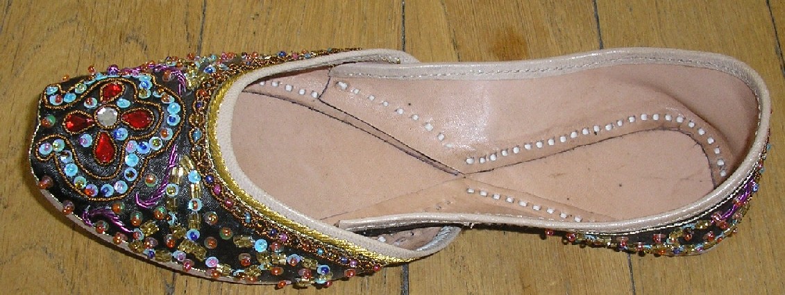 CHAUSSURE POUR FEMMES PRÉSENTANT LA FORME D'UNE BALLERINE, AVEC SEMELLE EXTÉRIEURE EN CUIR, AVEC DESSUS EN MATIÈRE TEXTILE , AVEC UNE SEMELLE INTÉRIEURE D'UNE LONGUEUR SUPÉRIEURE À 24 CM, SANS TALON. 

LE DESSUS DE LA CHAUSSURE EST COMPOSÉ DE DEUX PIÈCES DOUBLÉES INTÉRIEUREMENT DE CUIR, UNE RECOUVRANT LE DEVANT DE LA CHAUSSURE ET L'AUTRE L'ARRIÈRE, COUSUES ENSEMBLE AU NIVEAU DU MILIEU DE LA CHAUSSURE. IL EST COMPLÈTEMENT BRODÉ, DE VERROTERIES ET DE SEQUINS PRINCIPALEMENT.

LE POURTOUR DE LA CHAUSSURE EST POURVU D'UN BIAIS DE CUIR DE COULEUR CONTRASTÉE.