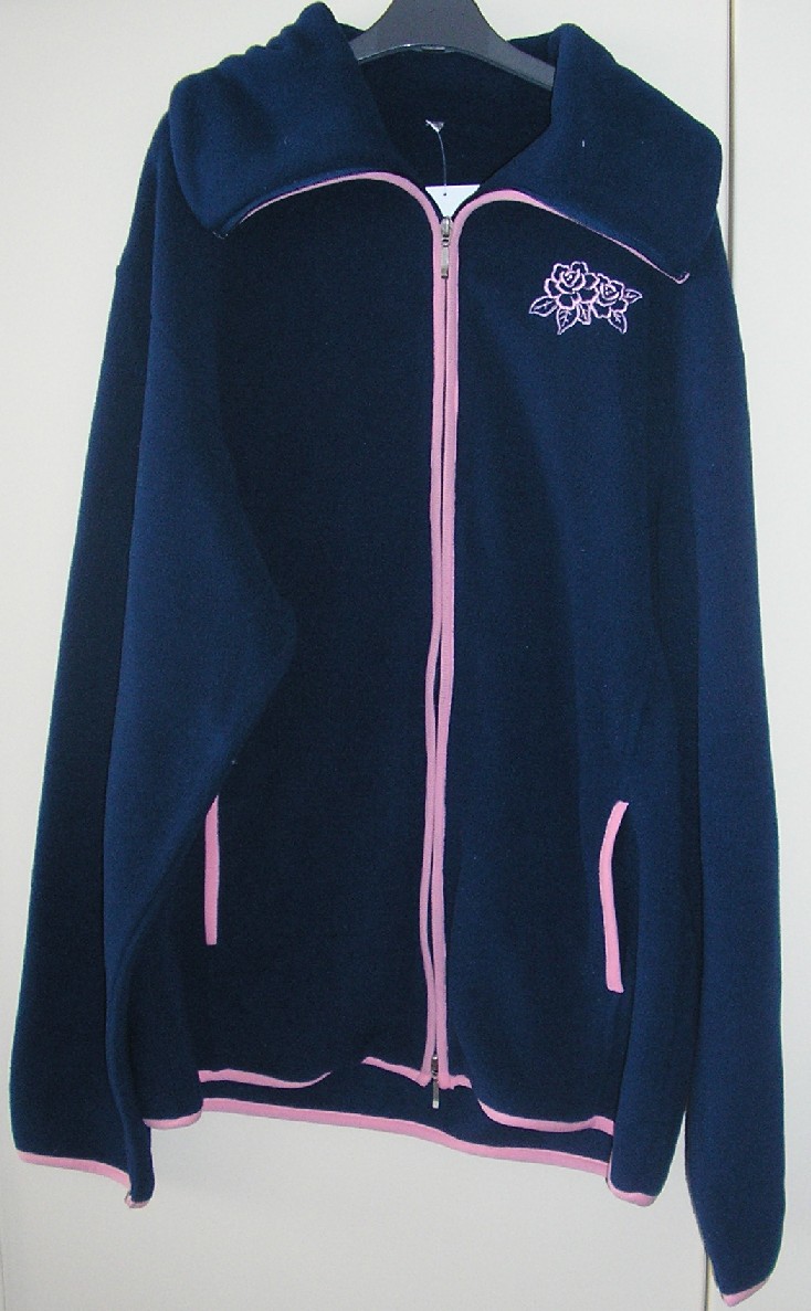 ENSEMBLE POUR FEMMES COMPOSÉ D'UN PANTALON ET D'UN VÊTEMENT DESTINÉ À RECOUVRIR LA PARTIE SUPÉRIEURE DU CORPS, DE TYPE GILET, RÉALISÉS DANS LA MÊME ÉTOFFE DE BONNETERIE DE FIBRE SYNTHÉTIQUE (100% POLYESTER) ASPECT POLAIRE, GRATTÉE À L'INTÉRIEUR, TEINTE UNIFORMÉMENT, CONDITIONNÉS ENSEMBLE POUR LA VENTE AU DÉTAIL : 

- LE GILET DESCEND SOUS LES HANCHES ET PRÉSENTE UN COL MONTANT, UNE OUVERTURE COMPLÈTE SUR LE DEVANT SE FERMANT À L'AIDE D'UNE FERMETURE À GLISSIÈRE, DES MANCHES LONGUES, DEUX POCHES LATÉRALES AINSI QU'UN LISERÉ DE COULEUR CONTRASTÉE SUR LE POURTOUR DE L'OUVERTURE, LE BAS DU VÊTEMENT ET AUX POCHES.

- LE PANTALON DESCEND JUSQU'AUX CHEVILLES, SANS OUVERTURE ET PRÉSENTE UNE BANDE ÉLASTIQUE À LA TAILLE, UNE POCHE LATÉRALE DE CHAQUE CÔTÉ AU NIVEAU DES HANCHES AVEC LISERÉ DE COULEUR CONTRASTÉE (MÊME COULEUR QU'EN HAUT) AINSI QU'UN OURLET À LA BASE. 

LES DEUX VÊTEMENTS COMPORTENT UN DESSIN BRODÉ, SUR LA POITRINE CÔTÉ GAUCHE POUR LE GILET ET SUR LE BAS DE LA JAMBE GAUCHE POUR LE PANTALON.