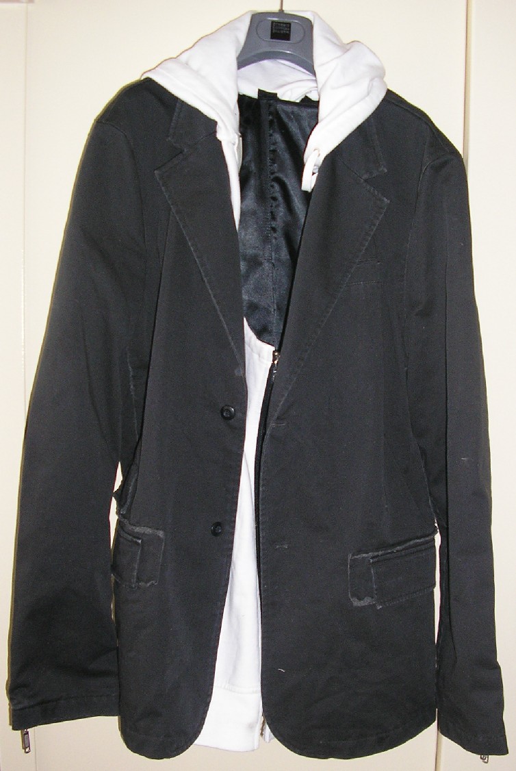 VESTE POUR HOMMES, EN TISSU DE COTON, DESTINÉE À COUVRIR LA PARTIE SUPÉRIEURE DU CORPS, COMPOSÉE DE DEUX PANNEAUX FRONTAUX, DEUX PANNEAUX DORSAUX ET UN PANNEAU DE CHAQUE CÔTÉ, AVEC UN COL TAILLEUR, AVEC DES MANCHES LONGUES DONT LES EXTRÉMITÉS PRÉSENTENT UNE OUVERTURE MUNIE D'UNE FERMETURE À GLISSIÈRE, AVEC UNE OUVERTURE COMPLÈTE SUR LE DEVANT SE FERMANT GAUCHE SUR DROITE À L’AIDE DE DEUX BOUTONS, AVEC UNE POCHE POITRINE COTE GAUCHE, AVEC DEUX POCHES AU NIVEAU DES HANCHES MUNIES DE RABATS ET FERMANT AU MOYEN DE BANDES VELCRO, AVEC UNE DOUBLURE COMPLÈTE, AVEC UNE POCHE INTERNE DU CÔTÉ GAUCHE, AVEC UNE FENTE DANS LE BAS DU DOS, AVEC UN OURLET A LA BASE. 

CET ARTICLE COMPORTE UN ACCESSOIRE DU VÊTEMENT EN ÉTOFFE DE BONNETERIE DE COTON, AMOVIBLE, CONSTITUÉ D'UN PLASTRON DOTÉ D’UNE CAPUCHE COMPORTANT UN CORDON COULISSANT RESSERRANT SUR SON POURTOUR. IL EST MAINTENU À L’INTERIEUR DE LA VESTE AU MOYEN D’UNE FERMETURE À GLISSIÈRE ET DE BANDES VELCRO.