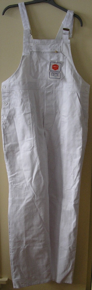 SALOPETTE POUR HOMMES, EN TISSU DE COTON, TEINT UNIFORMÉMENT, DE COUPE AMPLE, DESCENDANT JUSQU'AUX CHEVILLES. 

CE VÊTEMENT COMPORTE DES BRETELLES ÉLASTIQUÉES S'ATTACHANT SUR L'AVANT PAR DEUX BOUCLES EN MÉTAL, UNE BAVETTE AVEC UNE POCHE PLAQUÉE AVEC FERMETURE À GLISSIÈRE, UNE OUVERTURE D'AISANCE DE CHAQUE CÔTÉ SE FERMANT PAR DEUX BOUTONS, UNE OUVERTURE PARTIELLE AU NIVEAU DE L'ENTREJAMBE SE FERMANT GAUCHE SUR DROITE PAR DES BOUTONS ET DISSIMULÉE SOUS UN RABAT DE PROTECTION FORMANT BRAGUETTE, DEUX POCHES FENDUES SITUÉES AU NIVEAU DES HANCHES, UNE POCHE À L'ARRIÈRE DROIT AVEC FERMETURE À GLISSIÈRE ET AVEC UN OURLET À LA BASE.

IL S'AGIT D'UN VÊTEMENT DE TRAVAIL: IL EST IRRÉTRÉCISSABLE ET RÉSISTANT À TOUT SAUF AU FEU.