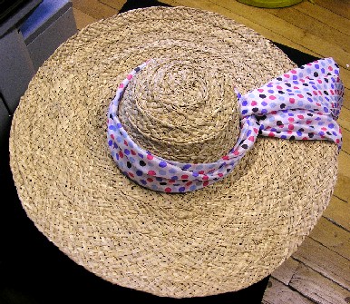 CHAPEAU DE PAILLE À CALOTTE FORMÉE ET À LARGE BORD CIRCULAIRE, GENRE CAPELINE, FABRIQUÉ PAR L'ASSEMBLAGE (EN SPIRALE) DE BANDES DE PAILLE TRESSÉE, D'UNE LARGEUR APPARENTE DE 2,5 CM.

CE CHAPEAU EST ORNÉ D'UN FOULARD EN TISSU IMPRIMÉ (100% SOIE) NOUÉ AUTOUR DE LA CALOTTE.