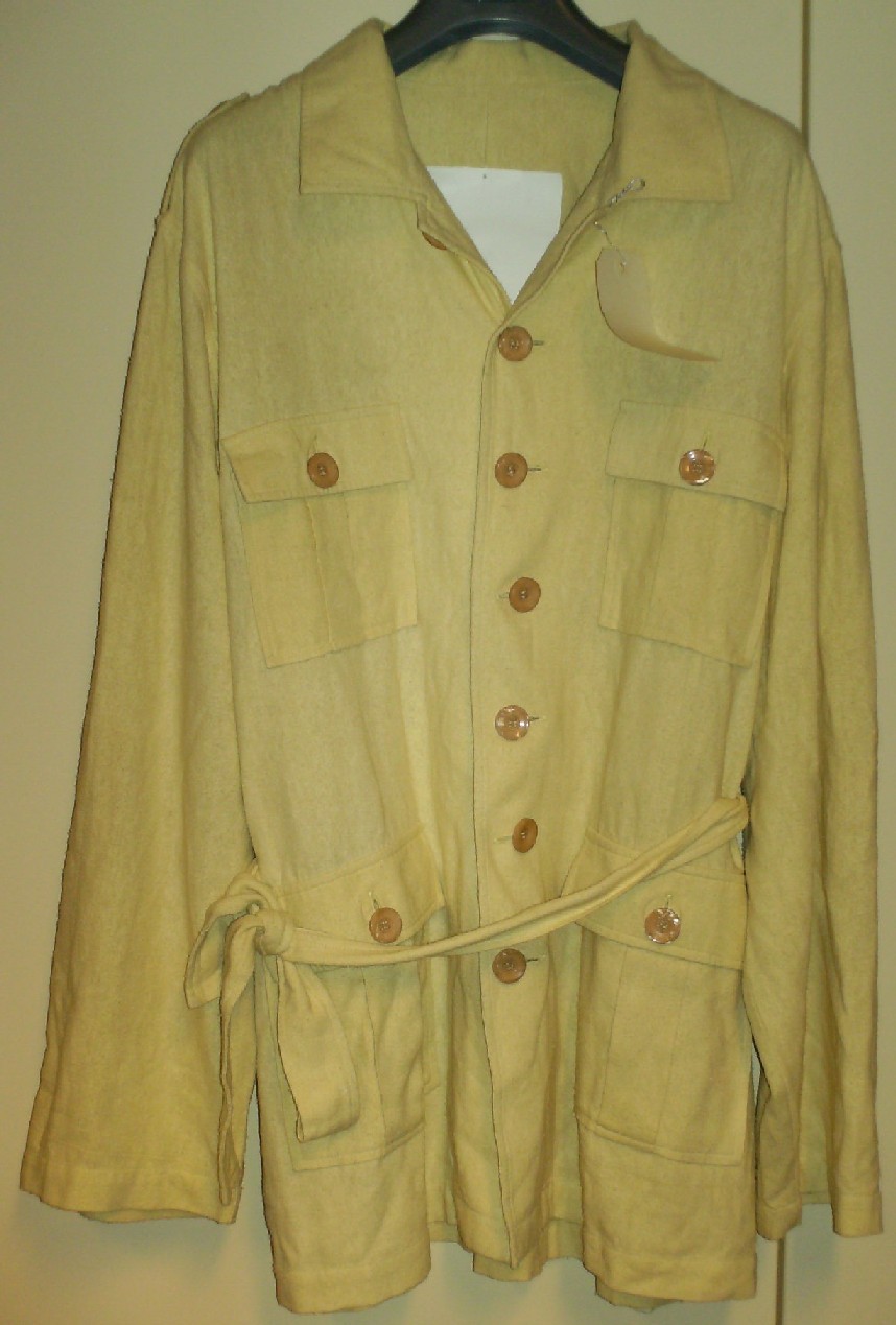 VESTE POUR HOMMES, DU TYPE SAHARIENNE, EN TISSU DE SOIE LÉGÈREMENT ÉMERISÉ, DESTINÉ À RECOUVRIR LA PARTIE SUPÉRIEURE DU CORPS, DESCENDANT SOUS LES HANCHES, AVEC 3 PANNEAUX COUSUS ENSEMBLE DANS LE SENS DE LA LONGUEUR, AVEC UN COL, AVEC DES MANCHES LONGUES POURVUES À LEURS EXTRÉMITÉS D'UN OURLET, AVEC UNE OUVERTURE COMPLÈTE SUR LE DEVANT SE FERMANT GAUCHE SUR DROITE AU MOYEN DE 7 BOUTONS, AVEC DEUX PATTES SUR LES ÉPAULES, AVEC DEUX POCHES AU NIVEAU DE LA POITRINE, AVEC DEUX POCHES SOUS LA TAILLE, AVEC UNE BANDE DU MÊME TISSU SERVANT DE CEINTURE AU NIVEAU DE LA TAILLE, AVEC UNE BASE OURLÉE.

CE VÊTEMENT PEUT ÊTRE PORTÉ PAR DESSUS D'AUTRES VÊTEMENTS.