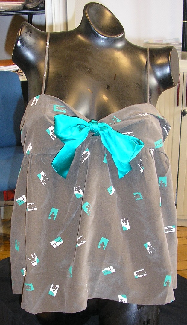 VÊTEMENT POUR FEMMES EN TISSU SATINÉ DE SOIE IMPRIMÉ DESTINÉ À RECOUVRIR LA PARTIE SUPÉRIEURE DU CORPS, GENRE BLOUSE, DESCENDANT JUSQU'À LA TAILLE, AVEC UNE ENCOLURE EN V TRÈS DÉCOLLETÉE, SANS MANCHES, AVEC DE FINES BRETELLES DE LA MÊME ÉTOFFE QUE LA BLOUSE, AVEC UN NOEUD SUR LE DEVANT À LA BASE DU DÉCOLLETÉ, AVEC UNE BASE OURLÉE.