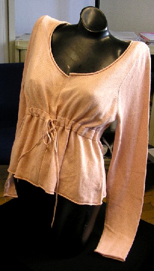 GILET POUR FEMMES, DE TYPE CARDIGAN, CONFECTIONNÉ EN ÉTOFFE DE BONNETERIE MAJORITAIREMENT DE SOIE (85% SOIE - 15% CACHEMIRE), COMPORTANT MOINS DE 10 RANGÉES DE MAILLES PAR CENTIMÈTRE LINÉAIRE, UNICOLORE, DESCENDANT JUSQU'AUX HANCHES. 

CE VÊTEMENT PRÉSENTE UNE ENCOLURE ARRONDIE, DES MANCHES LONGUES, UNE OUVERTURE COMPLÈTE SUR LE DEVANT, UN CORDON RESSERRANT À NOUER SUR LE DEVANT COULISSANT DANS UN BORD-CÔTE SITUÉ AU-DESSOUS DE LA POITRINE ET UNE BASE LÉGÈREMENT ÉVASÉE.

LE POURTOUR DU VÊTEMENT (ENCOLURE, EXTRÉMITÉ DES MANCHES ET BASE) PRÉSENTE UNE FINITION ROULOTTÉE.