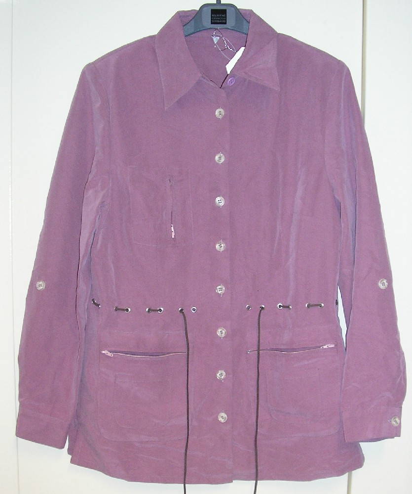 VESTE POUR FEMMES, CONFECTIONNÉE EN TISSU MAJORIATAIREMENT DE FIBRES ARTIFICIELLES (72% VISCOSE – 28% POLYESTER), UNICOLORE, AYANT DE LA TENUE,  CONSTITUÉE DE DEUX PANNEAUX FRONTAUX ET D'UN PANNEAU DORSAL COUSUS ENSEMBLE DANS LE SENS DE LA LONGUEUR, AJUSTÉE, NON DOUBLÉE ET DESCENDANT SOUS LES HANCHES. 
ELLE COMPORTE UN COL CHEMISE, UNE OUVERTURE COMPLÈTE SUR LE DEVANT SE FERMANT DROITE SUR GAUCHE AU MOYEN DE 9 BOUTONS, DES MANCHES LONGUES AVEC UNE OUVERTURE À LEUR EXTRÉMITÉ FERMÉE PAR UN BOUTON, DES ÉPAULETTES, DES POCHES SUR LE DEVANT SOUS ET AU DESSUS DE LA TAILLE, UNE CEINTURE FINE À LA TAILLE EN CUIR ET UNE FENTE DE CHAQUE CÔTÉ À LA BASE.