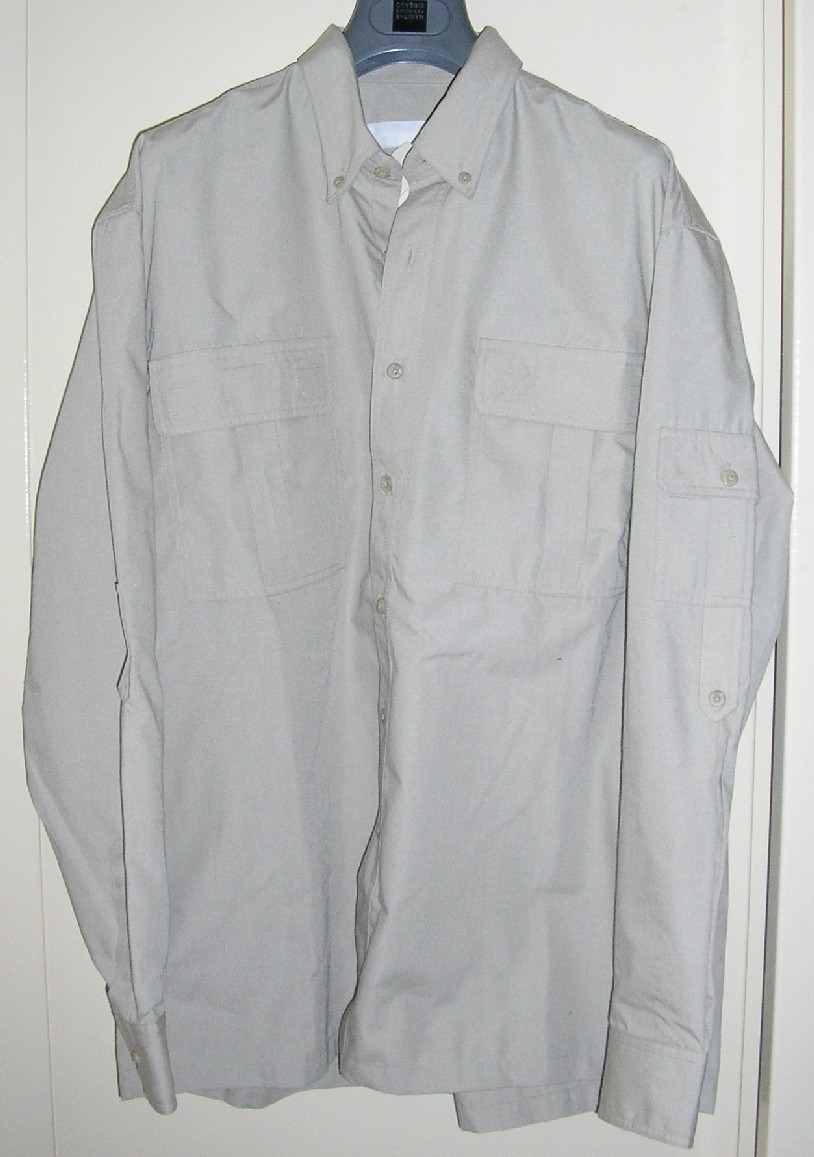 VÊTEMENT POUR HOMMES, DU TYPE CHEMISE, EN TISSU DE FIBRES SYNTHÉTIQUES MAJORITAIREMENT (65% POLYESTER, 35% COTON), UNICOLORE, DESTINÉ À RECOUVRIR LA PARTIE SUPÉRIEURE DU CORPS, DESCENDANT JUSQU'AUX HANCHES, AVEC UN COL, AVEC UNE OUVERTURE COMPLÈTE SUR LE DEVANT SE FERMANT GAUCHE SUR DROITE AU MOYEN DE 7 BOUTONS, AVEC DES MANCHES LONGUES POURVUES À LEUR EXTRÊMITÉ D'UNE OUVERTURE PARTIELLE SE FERMANT AU MOYEN D'UN BOUTON, AVEC DEUX POCHES AU NIVEAU DE LA POITRINE MUNIES D'UN RABAT FERMANT AU MOYEN DE BANDES VELCRO, AVEC UN PLI D'AISANCE DANS LE DOS, AVEC UNE BASE OURLÉE.