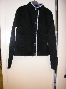 VETEMENT DESTINE A RECOUVRIR LA PARTIE SUPERIEURE DU CORPS, GENRE VESTE, POUR FEMMES, EN TISSU 98% COTON ET 2% SPANDEX, COMPORTANT UN COL MONTANT, UNE OUVERTURE COMPLETE SUR LE DEVANT AU MILIEU AVEC DES BOUTONS SE FERMANT DE DROITE SUR GAUCHE, DES MANCHES LONGUES SE TERMINANT PAR UNE BANDE DE TISSU, UNE POCHE VERTICALE DE CHAQUE COTE DU VETEMENT, LA BASE SE TERMINE PAR UNE BANDE DE TISSU, LOGO PUBLICITAIRE BRODE SUR LA MANCHE GAUCHE ET COUSU SUR LE BAS DU COTE DROIT.