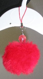 PENDENTIF POUR TELEPHONE PORTABLE SOUS LA FORME D’UNE BOULE DE POILS EN PEAU DE LAPIN DOTE D’UNE PERLE, D’UNE LANIERE ET D’UN ANNEAU DESTINE A L’ACCROCHER.
