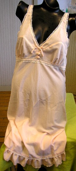 CHEMISE DE NUIT POUR FEMMES, DE TYPE NUISETTE, CONFECTIONNÉE EN TISSU DE FIBRES SYNTHÉTIQUES (100% POLYESTER) TEINT UNIFORMÉMENT, D'ASPECT SATINÉ, DE FACTURE SIMPLE, DESCENDANT JUSQU'AU-DESSUS DES GENOUX. 

CETTE NUISETTE PRÉSENTE DES BRETELLES RÉGLABLES, UNE ENCOLURE EN V TRÈS DÉCOLLETÉE SUR LE DEVANT, UN FIN GALON DE DENTELLE EN BORDURE DE L'ENCOLURE, UN PETIT NŒUD DÉCORATIF AU MILIEU DU DÉCOLLETÉ AINSI QUE DEUX BOUTONS DÉCORATIFS ET UN GALON DE DENTELLE RAPPORTÉ AU-DESSOUS DE LA POITRINE. 

LA BASE EST FORMÉE PAR UN VOLANT D'ENVIRON 6 CM DE LARGEUR.