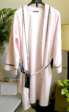 VETEMENT POUR FEMME, SIMILAIRE A UNE VESTE D’INTERIEUR, EN ETOFFE DE BONNETERIE ASPECT VELOURS DE COTON (100% COTON), DESTINE A COUVRIR LA PARTIE SUPERIEURE DU CORPS, DESCENDANT JUSQU’AUX GENOUX, DE FORME KIMONO, AVEC UNE ENCOLURE EN « V », AVEC UNE OUVERTURE COMPLETE SUR LE DEVANT SE FERMANT DROITE SUR GAUCHE EN S’ATTACHANT AU MOYEN D’UNE CEINTURE RETENUE PAR DES PASSANTS, AVEC DES MANCHES LONGUES POURVUES A LEURS EXTREMITES D’UNE BANDE RAJOUTEE DOTEE D’UN GALON EN SATIN ET DE PICOTS, AVEC UNE POCHE DE CHAQUE COTE DANS LA COUTURE, AVEC UN OURLET A LA BASE DU VETEMENT.

LE POURTOUR DE L’ENCOLURE ET LES PANNEAUX DU DEVANT SONT DOTES D’UN GALON EN SATIN ET DE PICOTS.