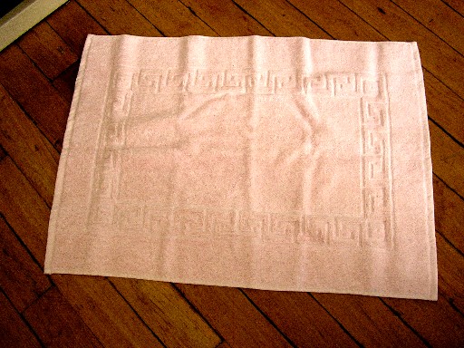 TAPIS DE BAIN, EN TISSU 100% COTON, BOUCLE DU GENRE EPONGE, DE DIMENSION 71CM X 53CM, AVEC MOTIFS GRECQUES, LES BORDURES SONT BORDEES D'UN BIAIS.