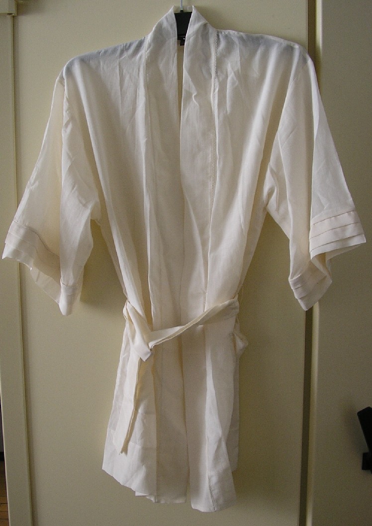 PEIGNOIR CONFECTIONNÉ EN TISSU MAJORITAIREMENT DE COTON (60% COTON – 40% SOIE), UNICOLORE, DESCENDANT JUSQU'À LA MI-CUISSE, COMPORTANT DES MANCHES 3/4, UNE OUVERTURE COMPLÈTE SUR LE DEVANT, UNE CEINTURE À LA TAILLE CONFECTIONNÉE DANS LA MÊME MATIÈRE SE GLISSANT DANS DES PASSANTS, DEUX POCHES AU NIVEAU DES HANCHES.