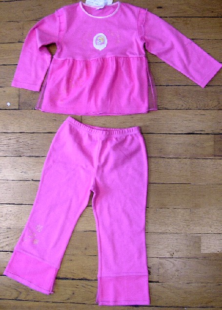 ASSORTIMENT D'ARTICLES POUR FILLETTES, CONDITIONNÉS ENSEMBLE POUR LA VENTE AU DÉTAIL, COMPRENANT UN ENSEMBLE ET UNE PAIRE DE PANTOUFLES.

L' ENSEMBLE EST COMPOSÉ DE DEUX VÊTEMENTS CONFECTIONNÉS DANS LA MÊME ÉTOFFE DE BONNETERIE 100% COTON, À MAILLES FINES ET TEINTE UNIFORMÉMENT, À SAVOIR : 
- UN VÊTEMENT DE TYPE PULL-OVER, DESCENDANT JUSQU'AUX HANCHES, COMPORTANT UNE ENCOLURE RAS-DU-COU BORDÉE D'UN BIAIS SATINÉ, DES MANCHES LONGUES OURLÉES À LEUR EXTRÉMITÉ, UN PETIT VOLANT EN TULLE RAPPORTÉ AUX EMMANCHURES, UN DESSIN FIGURANT UN PERSONNAGE IMPRIMÉ SUR LA POITRINE, PLUSIEURS MOTIFS FLORAUX PAILLETÉS AINSI QUE L'INSCRIPTION "PRINCESS" IMPRIMÉS SUR LE DEVANT ET UN LARGE VOLANT DE TULLE COUSU LÉGÈREMENT AU-DESSUS DE LA TAILLE ET DESCENDANT JUSQU'À LA BASE. LA BASE DU PULL-OVER EST OURLÉE.

- UN PANTALON, DESCENDANT JUSQU'AUX CHEVILLES, SANS OUVERTURE, AVEC UN BORD ÉLASTIQUE À LA TAILLE, AVEC UN LARGE VOLANT DE TULLE RAPPORTÉ AU BAS DES JAMBES ET AVEC DES MOTIFS FLORAUX PAILLETÉS SIMILAIRES À CEUX DU PULL-OVER, IMPRIMÉS SUR LA JAMBE GAUCHE.

LES PANTOUFLES PRÉSENTENT UN DESSUS ET UNE SEMELLE EXTÉRIEURE EN MATIÈRE TEXTILE (MÊME ÉTOFFE QUE LES VÊTEMENTS), UN GALON VOLANTÉ SUR LE POURTOUR DU DESSUS ET UN DESSIN FIGURANT UN PERSONNAGE AINSI QUE DES MOTIFS FLORAUX PAILLETÉS, SIMILAIRES À CEUX DE L'ENSEMBLE, IMPRIMÉS SUR LA CLAQUE.
