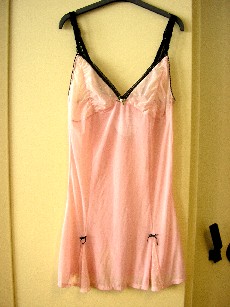 VETEMENT DESTINE A RECOUVRIR LE CORPS, GENRE CHEMISE DE NUIT, POUR FEMMES, EN BONNETERIE DE FIBRES SYNTHETIQUES, 90% POLYAMIDE ET 10% ELASTHANNE, COMPORTANT UNE ENCOLURE EN V TRES DECOLLETEE, DE FINES BRETELLES REGLABLES, DES PINCES POITRINE, UN VOLANT AU BAS DE CHAQUE COTE DU VETEMENT SUR LE DEVANT, LA BASE SE TERMINE PAR UN OURLET, AVEC DOUBLURE AU NIVEAU DE LA POITRINE, GALON DENTELLE EN BORDURE DE L'ENCOLURE ET DU DOS, PETITS NOEUDS AU MILIEU DE LA POITRINE ET A CHAQUE VOLANT.