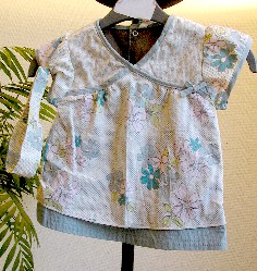 LOT COMPOSE DE DEUX VETEMENTS ET D’UN ACCESSOIRE DU VETEMENT POUR BEBE EN TISSU DE COTON 100% COTON :

- BLOUSE, AVEC UNE ENCOLURE EN « V », AVEC DES MANCHES COURTES DE FORME BALLON, AVEC UNE OUVERTURE COMPLETE DANS LE DOS SE FERMANT A L’AIDE DE BOUTONS-PRESSION, AVEC UNE DOUBLURE COMPLETE, AVEC UNE BANDE SURPIQUEE A LA BASE. LE POURTOUR DE L’ENCOLURE ET L’EXTREMITE DES MANCHES SONT DOTES D’UN BIAIS, AVEC UN PETIT NOEUD DECORATIF SUR LE COTE.

- PANTALON AVEC UN ELASTIQUE A LA TAILLE AU NIVEAU DU DOS, AVEC UNE OUVERTURE PARTIELLE SUR LE COTE SE FERMANT A L’AIDE D’UNE FERMETURE A GLISSIERE, AVEC UNE POCHE, AVEC UNE OUVERTURE COMPLETE AUX ENTREJAMBES SE FERMANT A L’AIDE DE BOUTONS-PRESSION.

- BANDEAU POUR CHEVEUX DOTE D’UN ELASTIQUE A L’ARRIERE.

TAILLE : 12 MOIS