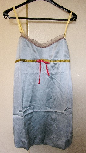 VETEMENT POUR FEMME, GENRE BLOUSE-CARACO, DE FACTURE AMPLE ET FLUIDE, TRES ELABOREE, EN TISSU DE SOIE (100% SOIE) DESTINE A COUVRIR LA PARTIE SUPERIEURE DU CORPS, DESCENDANT JUSQU'A MI-CUISSES, AVEC DEUX FINES BRETELLES REGLABLES, AVEC UN EMPIECEMENT DOTEE D’UNE ENCOLURE ARRONDIE GARNIE D’UN VOLANT EN MOUSSELINE, AVEC UN RUBAN DE SATIN ET UN NOEUD EN VELOURS SOUS LA POITRINE, AVEC UNE LARGE BANDE RAJOUTEE A LA BASE FORMANT OURLET.

LONGUEUR : 84 CM