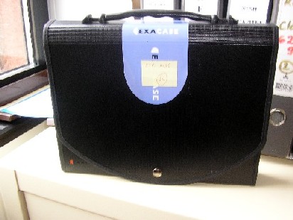 PORTE-DOCUMENTS DONT LA SURFACE EXTERIEURE EST EN MATIERE PLASTIQUE (PROLYPROPYLENE), EN FORME DE CARTABLE, COMPORTANT UNE POIGNEE, UN RABAT AVEC UNE FERMETURE PAR BOUTON-PRESSION, DES SOUFFLETS AVEC PORTE-ETIQUETTE, AVEC LOGO PUBLICITAIRE IMPRIME SUR LA FACE EXTERIEURE.