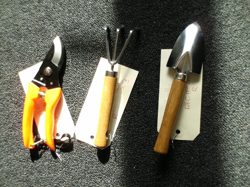 COFFRET POUR JARDINAGE COMPRENANT UN SECATEUR MANIE A UNE MAIN, UN PETIT RATEAU ET UNE PETITE PELLE.
LE SECATEUR A 2 LAMES METALLIQUES ET UN MANCHE EN PLASTIQUE, LE RATEAU ET LA PELLE SONT METALLIQUES ET CHACUN A UN MANCHE EN BOIS.