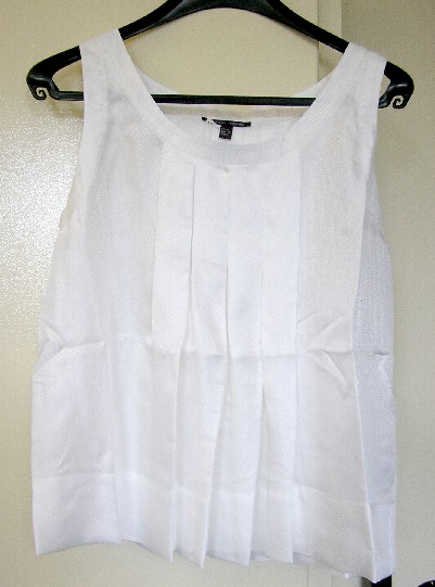 VETEMENT POUR FEMME, GENRE BLOUSE, DE FACTURE AMPLE ET FLUIDE, TRES ELABOREE, EN TISSU DE SOIE (100% SOIE) DESTINE A COUVRIR LA PARTIE SUPERIEURE DU CORPS, DESCENDANT JUSQU’AUX HANCHES, AVEC UNE ENCOLURE RONDE DECOLLETEE, SANS MANCHES, AVEC DES PLIS CREUX SUR LE DEVANT ET DANS LE DOS PARTANT DE L’ENCOLURE, AVEC UNE MARTINGALE MAINTENUE DANS LE DOS A L’AIDE DE DEUX PETITS BOUTONS, AVEC UN LARGE OURLET A LA BASE.

L’ENCOLURE ET LES EMMANCHURES SONT DOTEES SUR LEUR POURTOUR D’UNE BANDE RAJOUTEE DE FINITION.