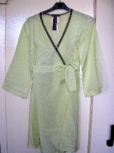VETEMENT LEGER DESTINE A RECOUVRIR LA PARTIE SUPERIEURE DU CORPS DESCENDANT JUSQU'A LA MI CUISSE,  EN TISSU DE COTON (100% COTON) POSSEDANT UNE ENCOLURE TRES DEGAGEE, DES MANCHES TROIS QUART OURLEES, AVEC UNE OUVERTURE COMPLETE SUR LE DEVANT, AVEC UN PAN DE TISSU COUSU AU NIVEAU DE LA TAILLE SE TERMINANT PAR DEUX LIENS QUI SE NOUENT DROITE SUR GAUCHE AFIN DE FERMER LE VETEMENT, DES FRONCES A LA TAILLE, AVEC UN LISERET DENTELLE SUR LE POURTOUR DE L'ENCOLURE ET UNE BASE OURLEE.
