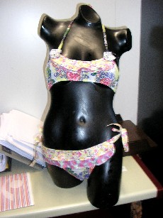 MAILLOT DE BAIN POUR FILLES, CONFECTIONNE EN TISSU 100% COTON, AVEC DES MOTIFS MULTICOLORES, COMPOSE:

-D'UN SOUTIEN GORGE COMPORTANT DES LIENS A NOUER AU COU ET DANS LE DOS, LA BORDURE DE LA BASE ET DES EMMANCHURES EST ELASTIQUEE, AVEC DEUX PETITS VOLANTS AU NIVEAU DE LA POITRINE ET UNE ROSACE DE CHAQUE COTE DU VETEMENT.

-D'UNE CULOTTE COMPORTANT DES LIENS A NOUER DE CHAQUE COTE AU NIVEAU DES HANCHES, LE FOND EST DOUBLE, LES BORDURES SONT ELASTIQUEES, AVEC DEUX PETITS VOLANTS SUR LE DEVANT ET AU DOS DU VETEMENT.