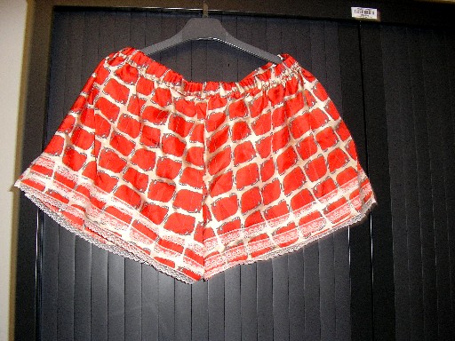 VETEMENT DESTINE A RECOUVRIR LA PARTIE INFERIEURE DU CORPS, GENRE SHORT, POUR FEMMES, CONFECTIONNE EN TISSU 100% SOIE, SANS OUVERTURE, AVEC UNE TAILLE ELASTIQUEE DANS LE DOS, DE LARGES ECHANCRURES A LA BASE DES CUISSES AVEC UNE FENTE DE CHAQUE COTE, AVEC POUR DECORATION DES BOUTONS ARGENTES SUR LE COTE GAUCHE, ET DE LA DENTELLE AU BAS ET A LA BASE DES CUISSES.