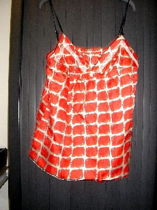 VETEMENT DESTINE A RECOUVRIR LA PARTIE SUPERIEURE DU CORPS, GENRE BLOUSE POUR FEMMES, CONFECTIONNE EN TISSU 100% SOIE, SANS MANCHES, COMPORTANT UNE ENCOLURE EN V, DE FINES BRETELLES REGLABLES, UNE BANDE ELASTIQUE EN BORDURE DU DOS, AVEC DECOUPES POITRINE, LA BASE SE TERMINE PAR UN OURLET SURFILE, AVEC POUR DECORATIONS DE LA DENTELLE AU NIVEAU DE LA POITRINE, ET UN BOUTON ARGENTE AU MILIEU DE LA POITRINE.