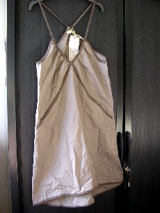 VETEMENT DESTINE A RECOUVRIR LE CORPS, GENRE ROBE POUR FEMMES, CONFECTIONNE EN TISSU 100% COTON, D'UNE LONGUEUR DE 96 CM POUR UNE TAILLE S, COMPORTANT UNE ENCOLURE EN V LEGEREMENT ARRONDIE, DE LARGES EMMANCHURES, DES BRETELLES ELASTIQUEES SE CROISANT DANS LE DOS, DES FRONCES AU NIVEAU DE LA POITRINE, UNE POCHE DE CHAQUE COTE DU VETEMENT, LA BASE EST LEGEREMENT ARRONDIE ET PLUS COURTE SUR LE DEVANT, ELLE SE TERMINE PAR UN BIAIS, LE HAUT DU DOS EST EN POINTE, LA BORDURE DE L'ENCOLURE ET DES EMMANCHURES SE TERMINE PAR UN BIAIS, AVEC LOGO ET MOTIFS BRODES AU BAS DU VETEMENT SUR LE DEVANT COTE GAUCHE.