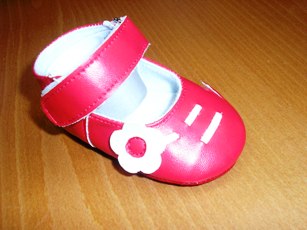CHAUSSURE POUR BEBE, GENRE BALLERINE, AVEC UN DESSUS EN MATIERE PLASTIQUE COUVRANT PARTIELLEMENT LE DESSUS DU PIED,  AVEC UNE BRIDE FERMANT PAR BANDE VELCRO AU NIVEAU DE LA CHEVILLE, AVEC UNE DOUBLURE EN MATIERE TEXTILE, AVEC UNE SEMELLE EXTERIEURE EN MATIERE TEXTILE, AVEC UN MOTIF DECORATIF EN FORME DE FLEUR COUSU SUR LE COTE EXTERNE DE LA CHAUSSURE.