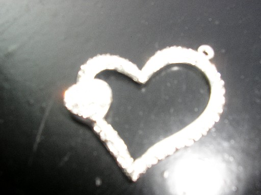 BIJOU FANTAISIE, PENDENTIF EN FORME DE COEUR, EN ZINC ARGENTE, COMPORTANT SUR LA PARTIE AVANT DES STRASS EN VERRE.