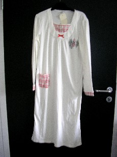 VETEMENT DESTINE A RECOUVIR LE CORPS, GENRE CHEMISE DE NUIT, POUR FEMMES, CONFECTIONNE EN ETOFFE DE BONNETERIE 60% COTON ET 40% POLYESTER, COMPORTANT UNE ENCOLURE ARRONDIE, UN PLASTRON AVEC UNE FAUSSE OUVERTURE ET DES BOUTONS, DES MANCHES LONGUES, UNE POCHE COTE DROIT SUR LE DEVANT, LA BASE DU VETEMENT SE TERMINE PAR UN OURLET ET UNE FENTE DE CHAQUE COTE, AVEC DES MOTIFS BRODES COTE GAUCHE AU NIVEAU DE LA POITRINE, UN PETIT NOEUD AU CENTRE DE L'ENCOLURE, L'EXTREMITE DES MANCHES, LE PLASTRON, LA POCHE ET UNE BRODERIE SONT ASSORTIS.