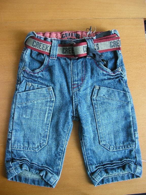 PANTALON POUR BÉBÉ, EN TISSU DE COTON (ASPECT DENIM), DESCENDANT JUSQU'AUX CHEVILLES, AVEC UN ÉLASTIQUE A LA TAILLE AU NIVEAU DU DOS, AVEC UNE OUVERTURE PARTIELLE SUR LE DEVANT SE FERMANT GAUCHE SUR DROITE A L’AIDE D’UN BOUTON-PRESSION, AVEC CINQ POCHES SUR LE DEVANT ET DEUX POCHES PLAQUÉES SUR L'ARRIÈRE DU PANTALON ET UN OURLET A LA BASE SURMONTÉE DE FRONCES DÉCORATIVES. 
EN OUTRE, LE PANTALON PRÉSENTE UNE CEINTURE EN POLYESTER, RÈGLABLE PAR BOUCLE, MAINTENUE PAR CINQ PASSANTS, DES COUTURES APPARENTES ET DES PETITES PASTILLES MÉTALLIQUES DÉCORATIVES. 
ENFIN, LE NOM DE LA MARQUE EST COUSU SUR LA POCHE DROITE ARRIÈRE, INSCRIT SUR LA CEINTURE ET GRAVÉ SUR LE BOUTON-PRESSION ET LES PASTILLES MÉTALLIQUES.

TAILLE : 6 MOIS